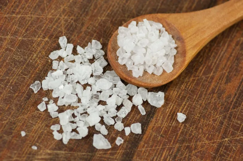 gros sel de mer se bouchent sur une planche à découper sombre