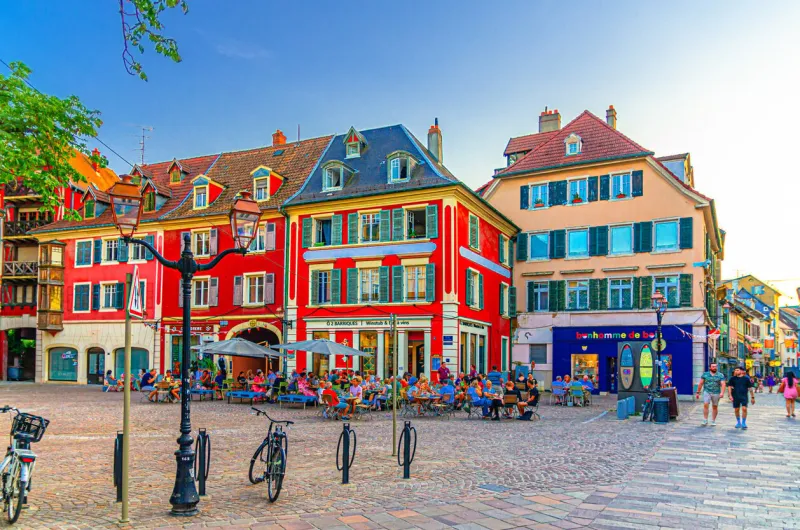 mulhouse, france, july 10, 2024  people sitting at tables of street restaurant outdoor cafÃ© and colorful houses on pedestrian square in old town mulhouse city historic centre, alsace grand est region