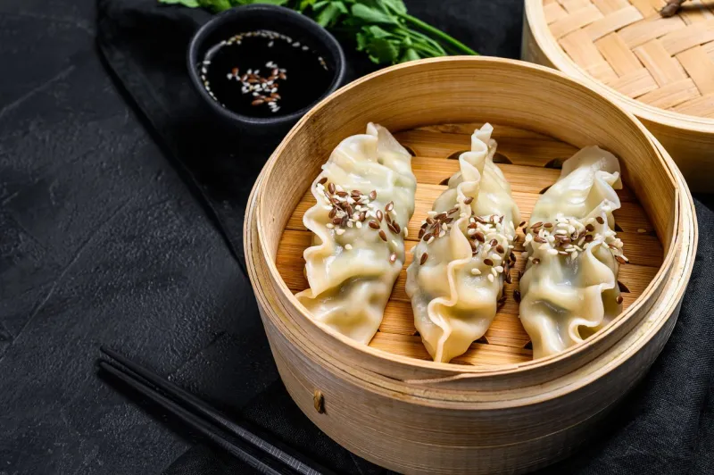 japanese gyoza in a traditional bamboo steamer top view space for text rustic old vintage black background
