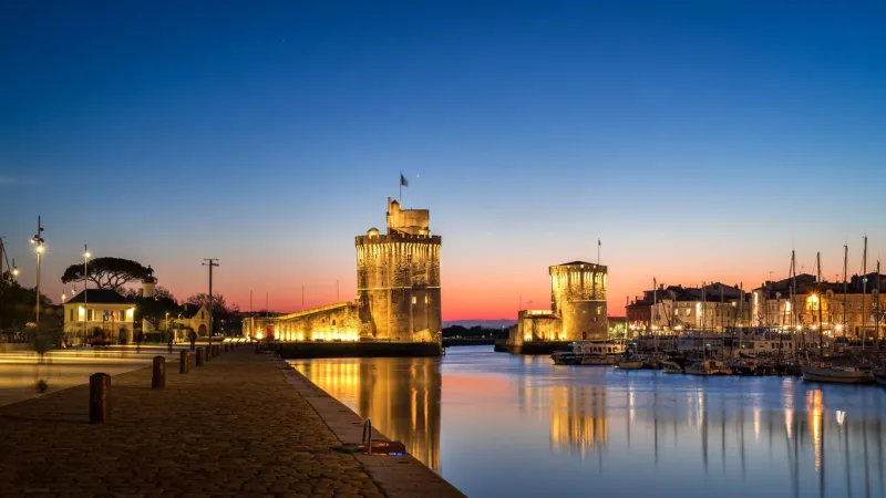 panoramic view of the old harbor of la rochelle at blue hour with its famous old towers