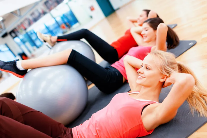 fitness, sport, training, gym and lifestyle concept - group of smiling people working out in pilates class