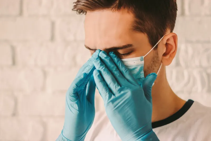 frustrated tired man in protective gloves on hands and medical face mask feeling headache exhausted sick surgeon doctor in protective mask on face and medical gloves coronavirus covid-19 symptoms
