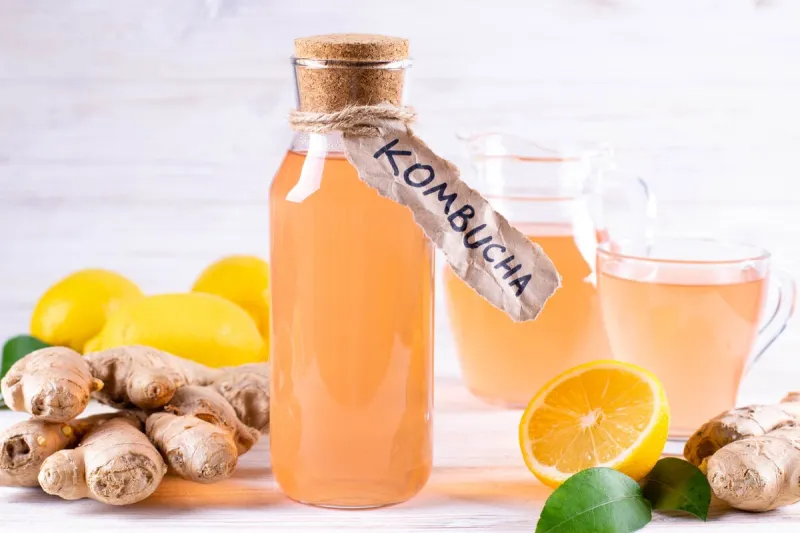 refreshing filtered kombucha tea in a glass bottle and a glass, with label written kombucha on white wooden background