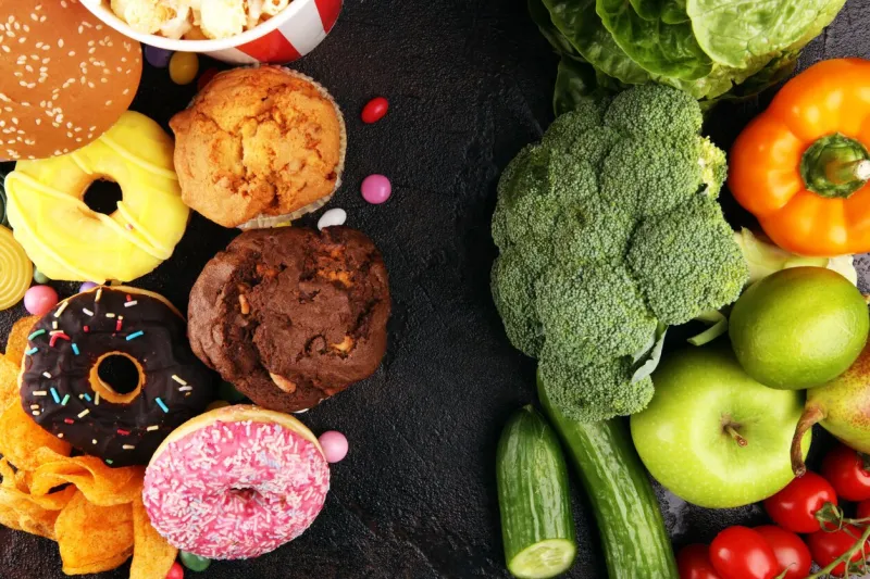 healthy or unhealthy food concept photo of healthy and unhealthy food fruits and vegetables vs donuts,sweets and burgers on dark