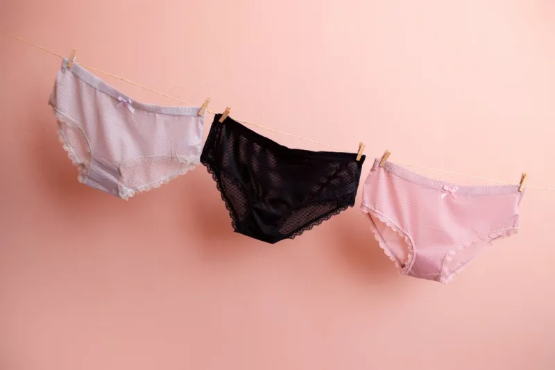 colorful clean women's panties hang on a rope on a pink isolated background