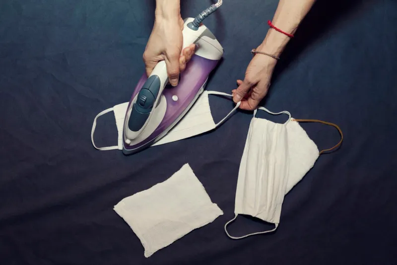 female human hands in ironing handmade protective mask selective focus