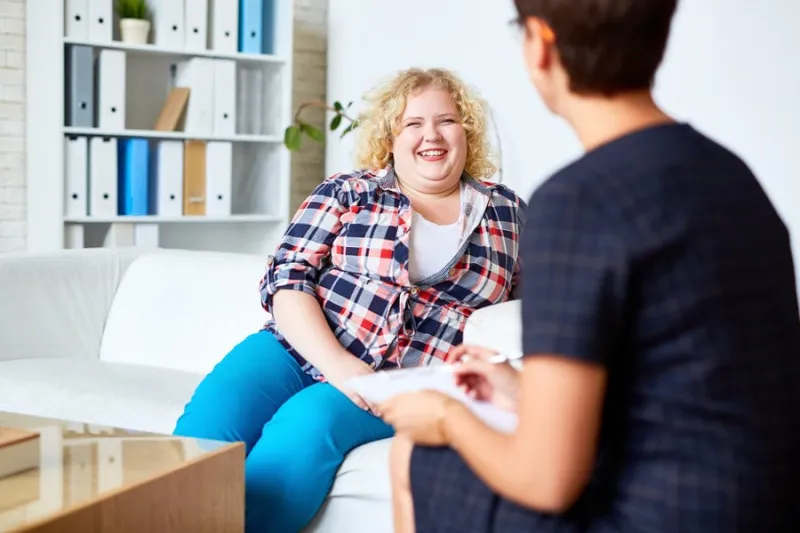 happy patient with overweight talking to her psychologist