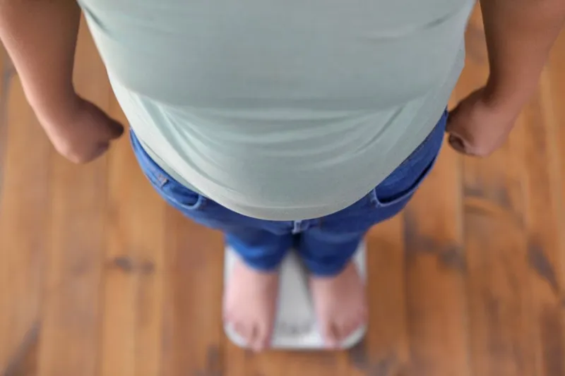overweight boy standing on floor scales indoors, above view