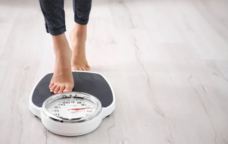 woman measuring her weight using scales on floor