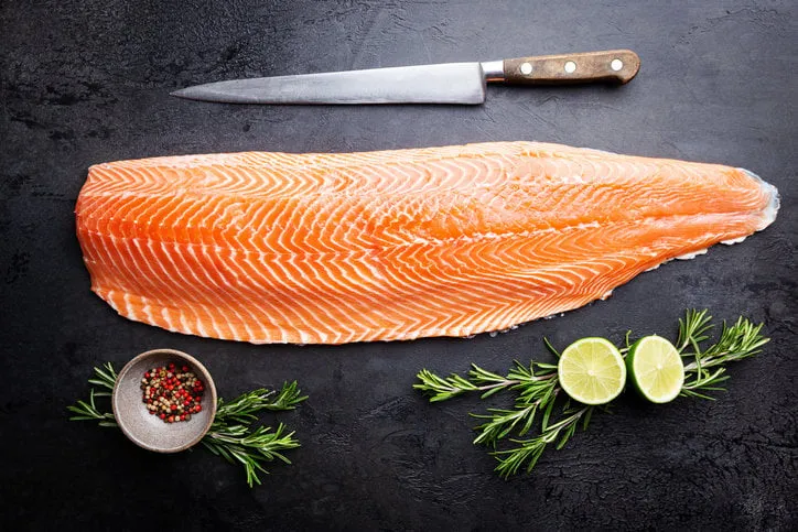 fresh raw salmon or trout sea fish fillet with spices and herbs on black background, top view
