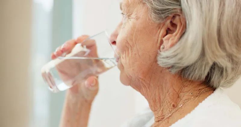 healthy, hydration and senior woman drinking water for wellness and liquid diet detox at home thirsty, fresh and calm elderly female person enjoying glass of cold drink in modern retirement house
