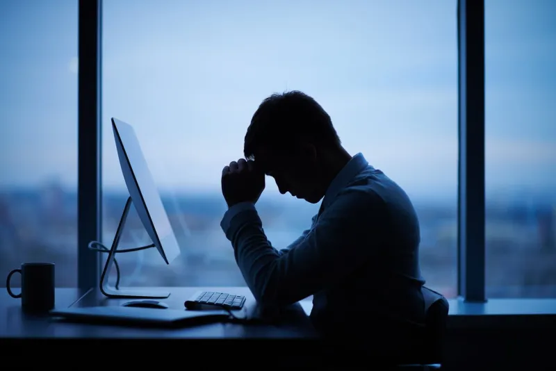 tired or stressed businessman sitting in front of computer in office