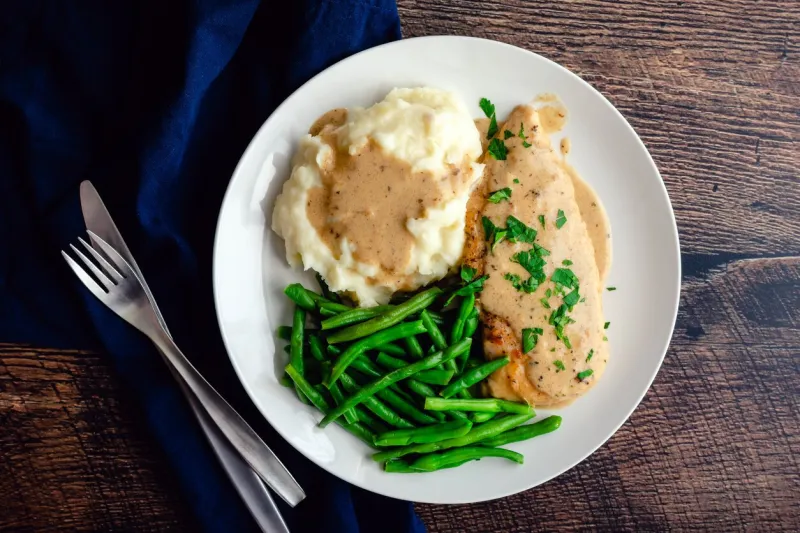 chicken breast served with green beans, mashed potatoes, and garlic gravy  chicken cutlet topped with creamy garlic sauce served with vegetables