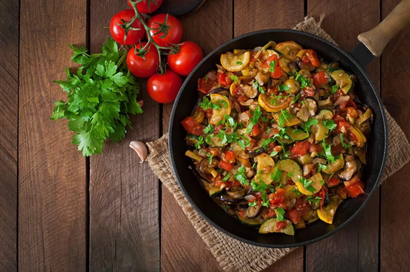 vegetable ratatouille in frying pan on a wooden table