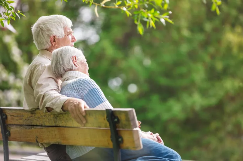 elderly couple resting on a bench in the park