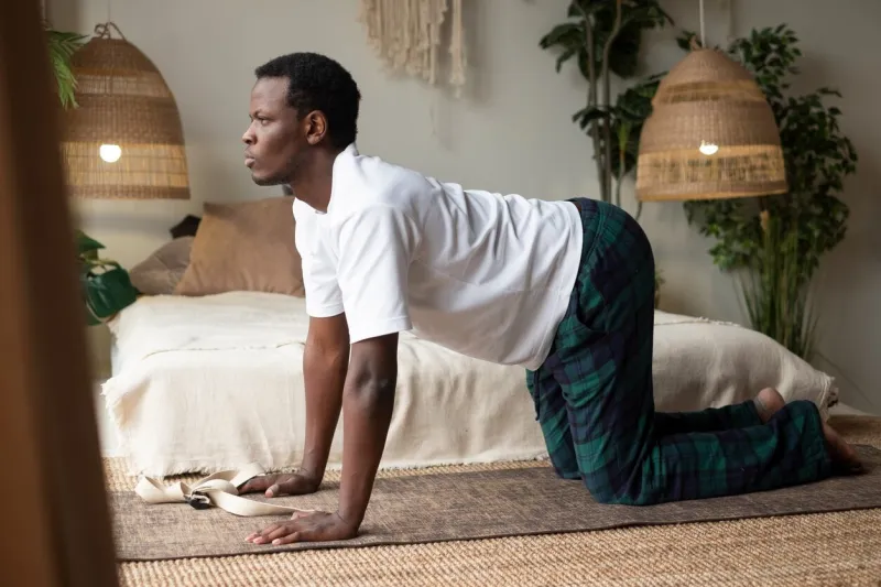 sporty muscular young african man working out, yoga, pilates, fitness training, bend in cow yoga posture, bitilasana