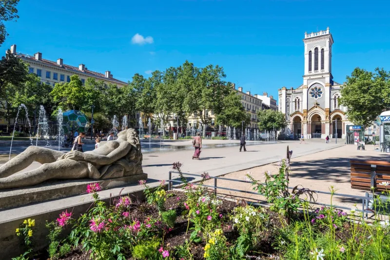 saint-etienne, france - july 29, 2019 the square of jean jaures in saint etienne downtown with fountains morini andre catholic church is at right background