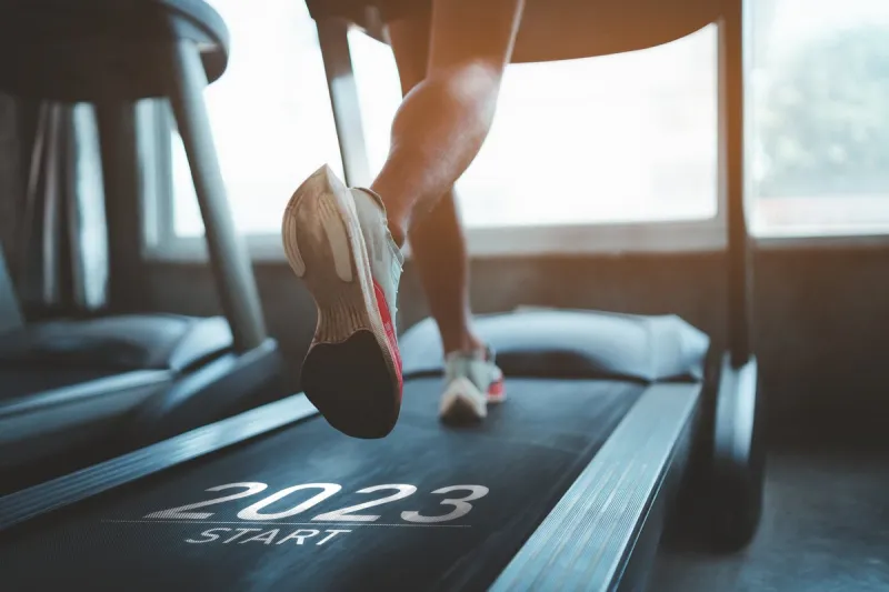 happy new year 2023,2023 symbolizes the start of the new year close up of feet, sportman runner running on treadmill in fitness club cardio workout healthy lifestyle, guy training in gym