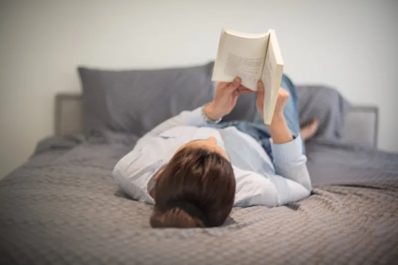 relaxing with a good read woman on bed reading book