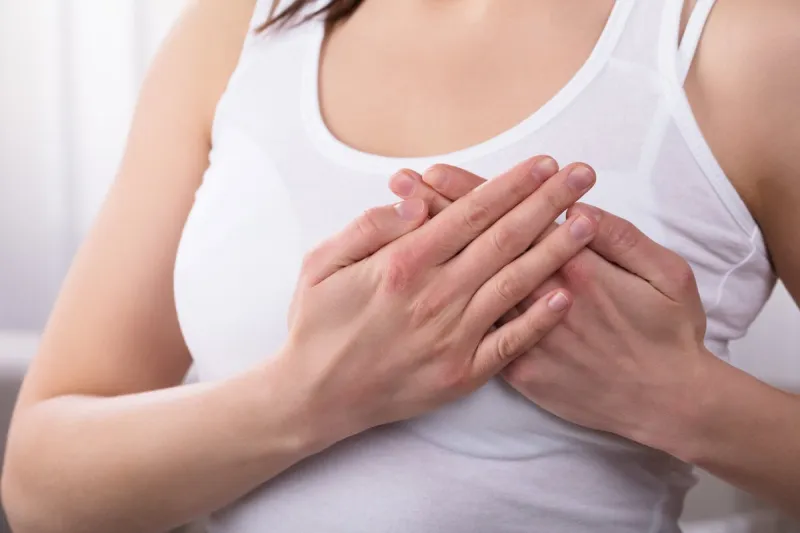 close-up of a woman's hand on breast suffering from pain