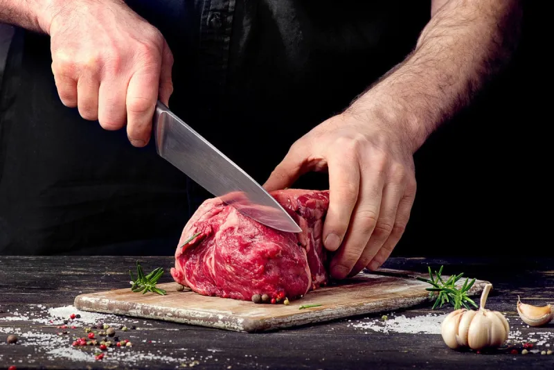 man cutting raw beef meat