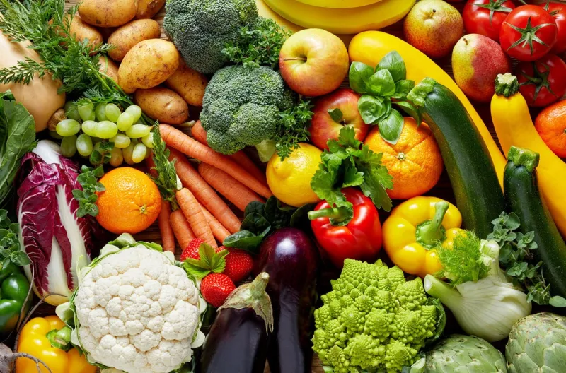 different colorful fruits and vegetables all over the table in full frame studio shot