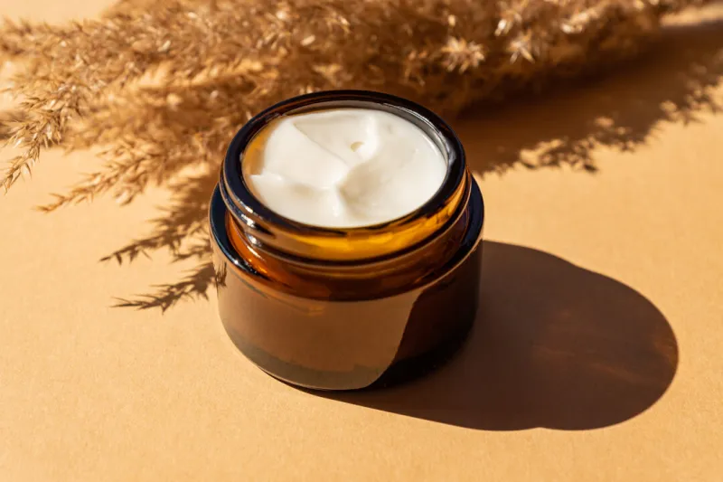close up of collagen cream in glass jar and dry flowers reeds on beige background skin and body care beauty products