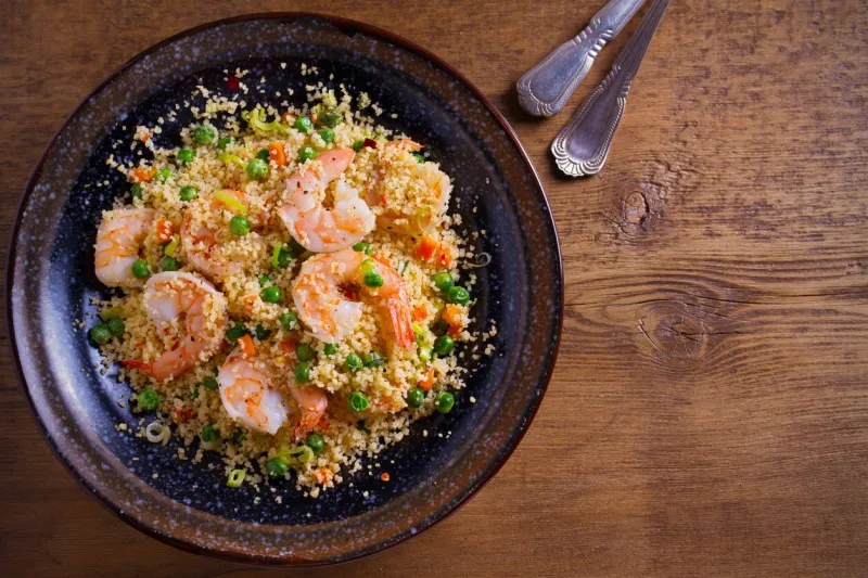 shrimps with couscous, green peas, leeks and carrot overhead, horizontal