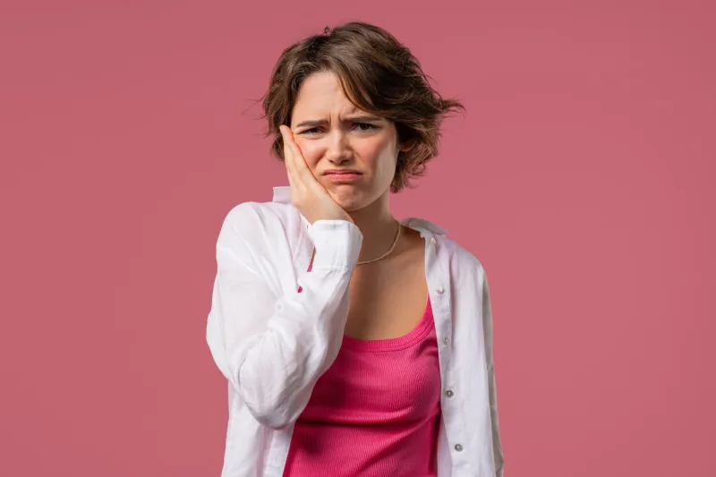 pretty young girl with tooth pain on pink studio background toothache, dental problems, dentistry and medicine concept