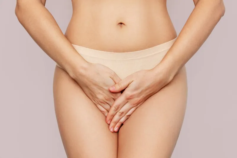 cropped shot of a young woman in underwear holding her crotch with her hands, suffering from cystitis isolated on beige background gynecological problems, genital tract infections healthcare concept