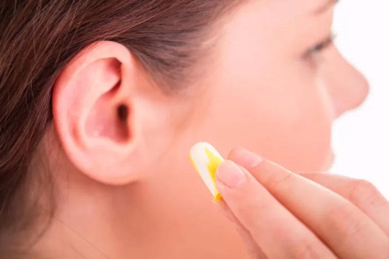 femme appliquer des bouchons d'oreille dans l'oreille - gros plan