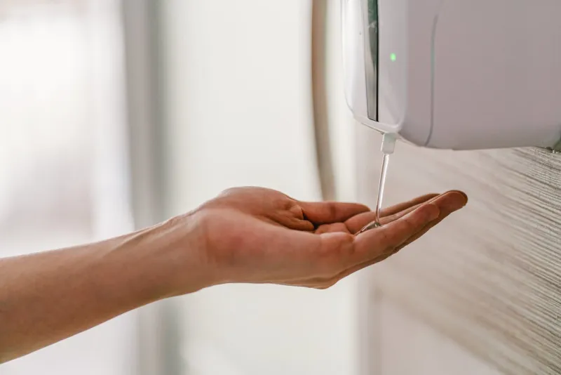 asian woman hand using wash hand sanitizer gel dispenser automatic machine for prevent coronavirus