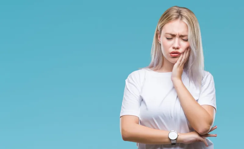 young blonde woman over isolated background touching mouth with hand with painful expression because of toothache or dental illness on teeth dentist concept