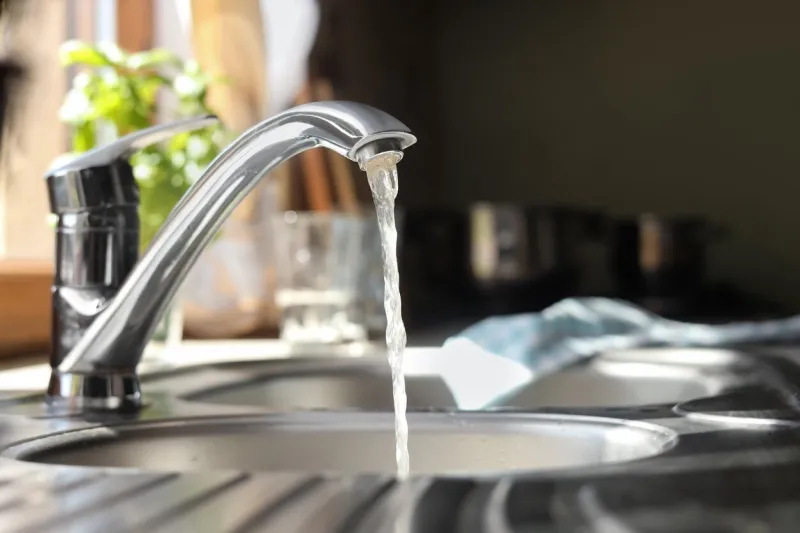 water running from tap into kitchen sink