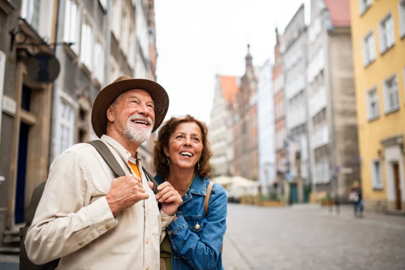 a portrait of happy senior couple tourists outdoors in historic town