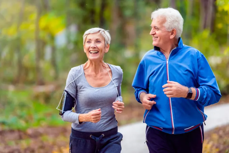 senior active couple running, walking and talking in the park healthy lifestyle
