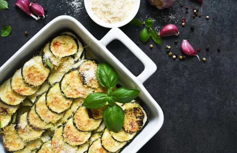 zucchini casserole with cream, garlic and parmesan on a black background view from above