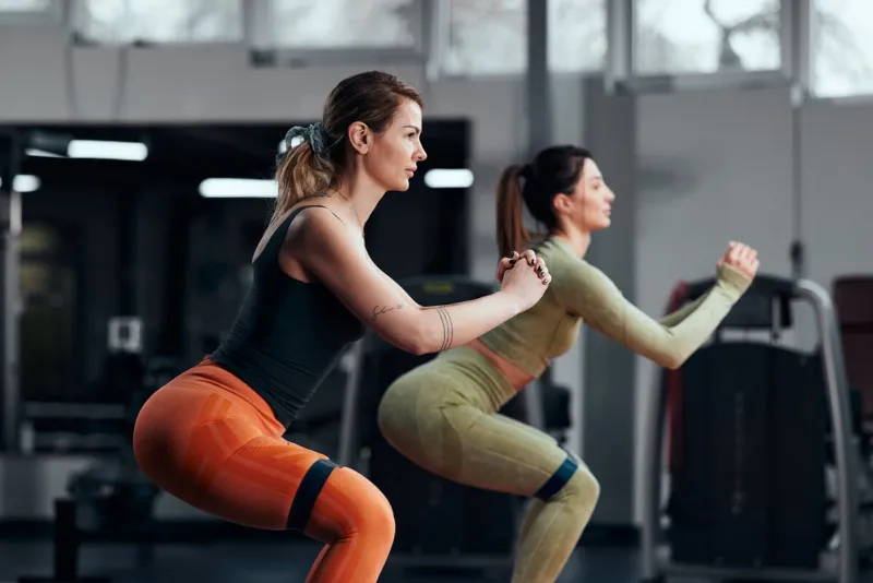sporty women in gym exercising with elastic resistance rubber band