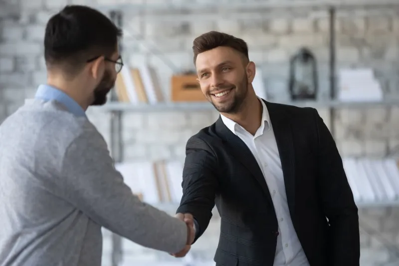 smiling young businessmen shake hands get acquainted greeting at office meeting, happy motivated male business partners handshake closing dal or making agreement at briefing, partnership concept