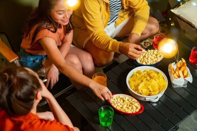 group of diversity adult asian people friends enjoy meeting party with eating snack potato chip and soft drink at home outdoor rooftop celebration holiday event new year vacation with happiness