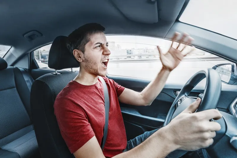 angry man driver reacts aggressively to other road users concept of psychological problems, anger, and traffic accidents