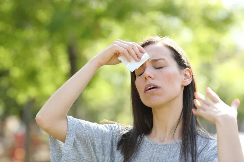 woman drying sweat using a wipe in a warm summer day