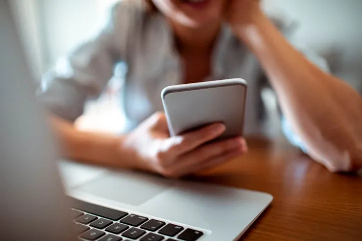 close up of a young woman using her phone at home