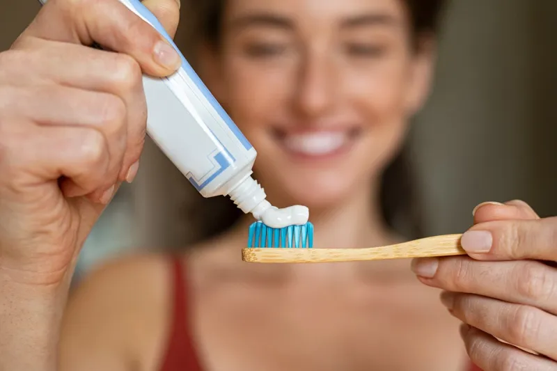 close up of woman with tooth brush applying paste in bathroom closeup of girl hands squeezing toothpaste on ecological wooden brush smiling beautiful woman applying toothpaste on eco friendly toothbrush