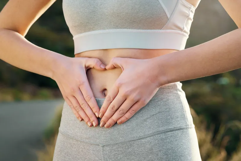 shot of a fit young woman forming a heart shape over her stomach