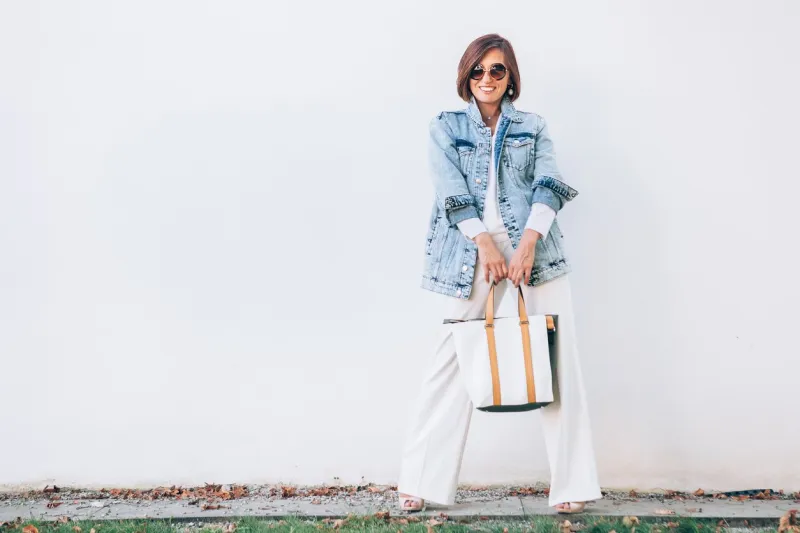 elegant woman dressed in oversize denim jacket and wide white trousers