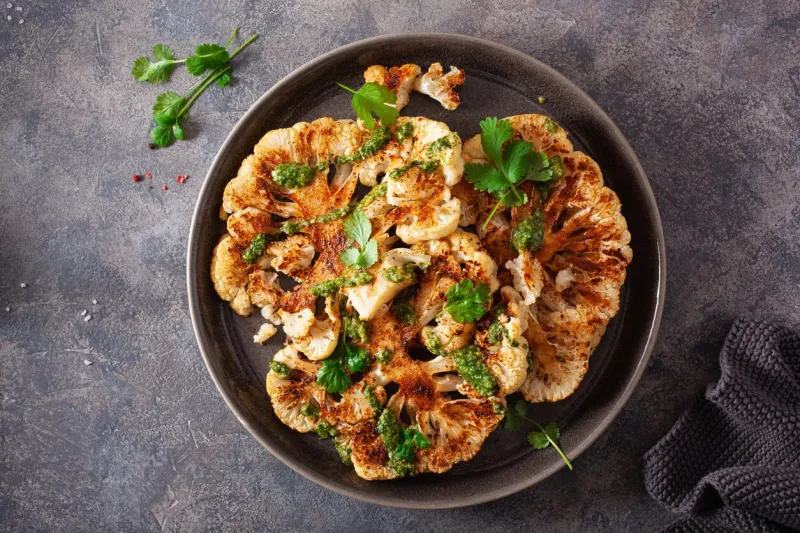 cauliflower steaks with herb sauce and spice plant based meat substitute