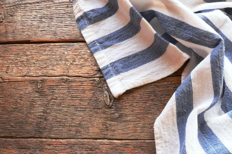 a top view image of a dish towel on an old wooden kitchen table top