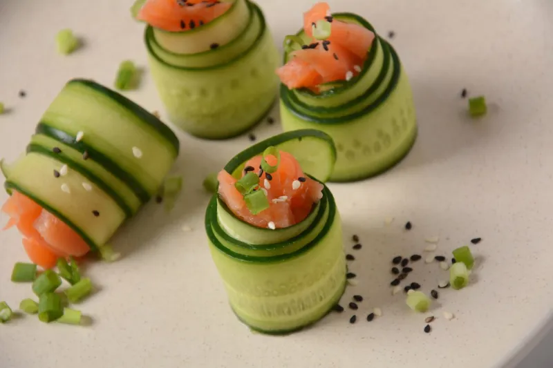 cucumber rolls with pieces of salted salmon, black and white sesame seeds, chopped green onion holiday vegetable appetizers