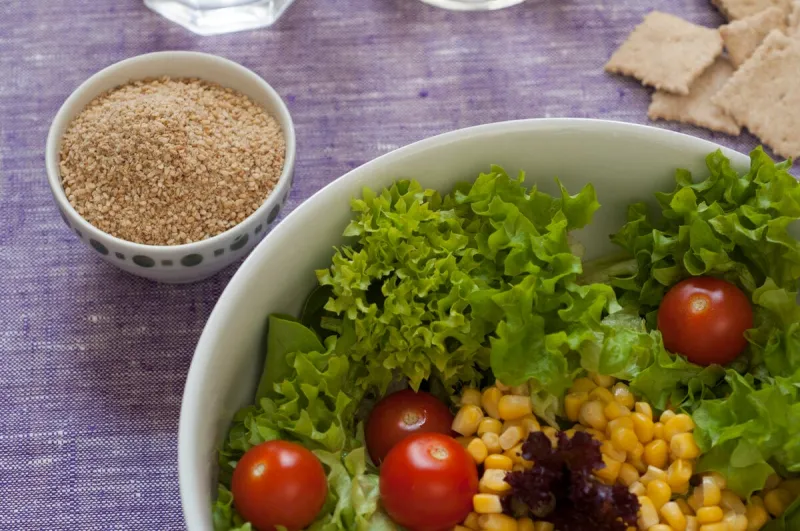 close-up view of fresh organic mixed salad  lettuce, sweet corn, tomato gomasio condiment on the left